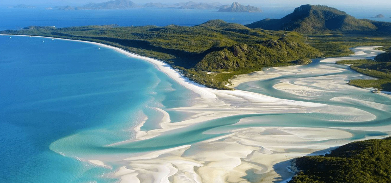 Whitsundays yacht charter itinerary. Swirling sands of a river and ocean of the Whitsunday Island viewed from a luxury yacht charter
